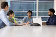 © fizkes - Confident Indian business team leader man holding corporate meeting at office table, talking to employees, sitting on bosses place at large conference desk, speaking, brainstorming