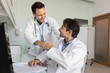 © fizkes - Two happy male doctors giving high five at workplace in clinic office, lab, examination room, joining hands in support motivation gesture, enjoying good teamwork result, successful cooperation