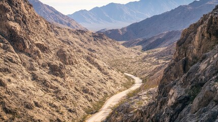 Poster - Winding Scenic Road Through Desert Valley Surrounded by Rocky Cliffs and Majestic Mountains Under Clear Blue Sky