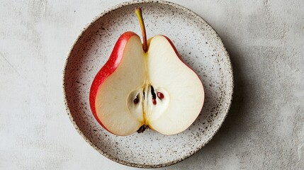Poster - Halved peeled red pear on a speckled plate showcasing organic healthy food and natural products for culinary use and nutrition concepts