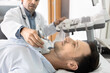© fizkes - Clinic patient man lying on couch on ultrasound scanning procedure, checking thyroid, lymph nodes, glands. Sonographer doctor examining man, using modern medical computer for ultrasonography