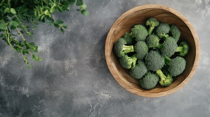 Poster - Fresh organic broccoli in wooden bowl on rustic table top with green herbs in the background healthy eating concept top view image