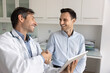 © fizkes - Cheerful Latin patient giving handshake to doctor with gratitude, thanking for consultation, medical checkup, recommendation. Latin practitioner shaking hand with man visiting clinic