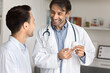 © fizkes - Happy medical professional specialist man recommending vitamins, medical supplement to patient for successful therapy, showing pills bottle to patient, smiling, giving consultation