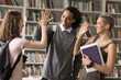 © fizkes - Student life style. Excited teenage high schoolers of diverse gender ethnicity join palms in high five with adolescent female friend as greeting parting gesture agree with mate express support unity