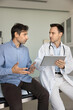 © fizkes - Serious doctor meeting with patient in examination room, making notes, electronic records on tablet, using digital computer pad on appointment listening to mans complaints