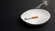 © อาริษา วันดี - Elegant White Ashtray with a Cigarette Resting on Its Textured Surface, Smoke Wisps Rising Against a Dark Background