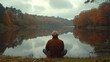 © ATVPEDIA ID - Man meditates by autumn lake, serene forest reflection. Use Relaxation, mindfulness.
