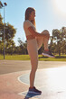 © astrosystem - Young woman relaxing and jumping after exercise in urban park during sunny summertime day.