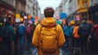 © Creative_art - A person in a yellow jacket stands amidst a crowd holding colorful protest signs.
