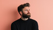 © NaphakStudio - thoughtful man with beard gazes upward against peach background. His expression reflects contemplation and confidence.