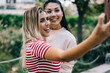 © BullRun - Happy multiracial female bloggers millennial influencers making selfie on smartphone camera, cheerful woman best friends spending time together outdoors having fun making pictures on mobile phone