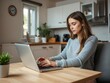 © Chalermrach - Woman sitting at kitchen table working on laptop computer, freelance, technology