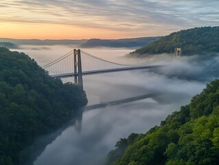 Poster - Sunrise over a suspension bridge shrouded in mist, nestled in a lush green valley.
