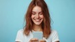 © Katarina - A cheerful woman interacts with her phone, smiling at the screen, set against a bright blue background, suggesting happiness and modern connectivity.