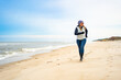 © Jacek Chabraszewski - Beautiful mature woman running along seashore on sandy beach in wintertime