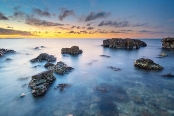 Wall Mural - beautiful nature seascape of beach shore among rocks on evening sunset.