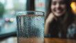 © Евгений Архипов - A close-up of a frosted glass with condensation, a girl smiling on the other side in the background.