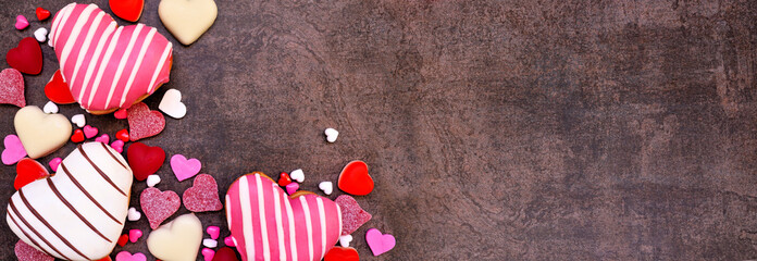 Aufkleber - Valentines Day heart shaped sweets corner border with donuts and candies. Top view on a dark stone banner background with copy space.