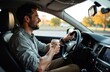 © Vasilii - A man drives a car with coffee in his hands