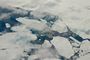 aerial view of broken sea ice with thin clouds.