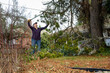 © knelson20 - Middle aged woman with loppers, long handle clippers, cleaning up after the storm, large branch broken on pine tree in a windstorm, residential yard weather damage