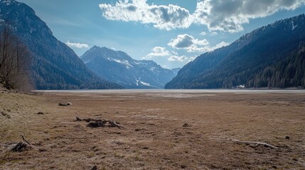 Poster - A breathtaking springtime landscape of the dried Achensee surrounded by majestic mountains under a blue sky with fluffy clouds.