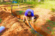 © ungvar - Worker in garden, digging, installing PVC water pipe for new irrigation system in rich, brown soil