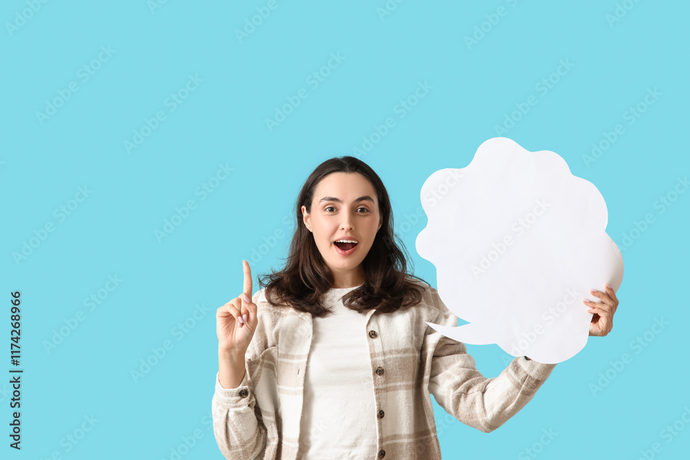 Young woman with blank speech bubble pointing at something on blue background