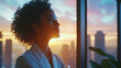 © PACHARA - A woman with curly hair is looking out a window at the sunset