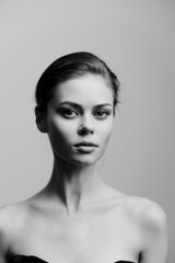 Poster - Black and white portrait of a young woman with an elegant hairstyle, expressing confidence and strength. Minimalistic background enhances her striking features.