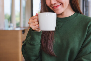 Poster - Closeup image of a young woman holding a cup of hot coffee