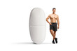 © Ljupco Smokovski - Full length portrait of a bodybuilder standing next to a big pill