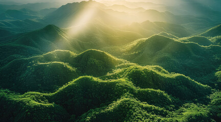 Poster - Lush green mountains and rolling hills with beams of sunset light permeating through foliage. Aerial high view.