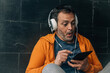 © tetxu - middle aged man with headphones and surprised gesture sitting on the street using digital tablet