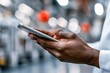 © Peeradontax - A close-up image of hands holding a sleek tablet in a professional setting. The blurred industrial background features subtle bokeh lighting, emphasizing the focus on the user and the device.