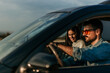 © La Famiglia - Happy couple driving together, enjoying a scenic sunset on a road trip