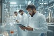 © Peeradontax - A male scientist in a white lab coat and safety goggles examines data on a tablet in a cutting-edge laboratory.