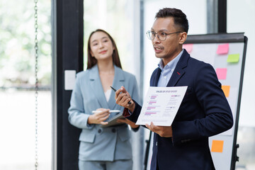 Wall Mural - Asian businessman and businesswoman looking at laptop computer in the workplace office, Feeling happiness
