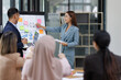 © David - Asian female ceo and multicultural business people discussing company presentation at boardroom table. Diverse corporate team working together in modern meeting room office.