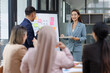 © David - Asian female ceo and multicultural business people discussing company presentation at boardroom table. Diverse corporate team working together in modern meeting room office.