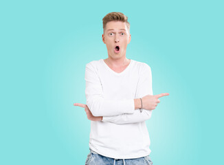 Man in a white shirt pointing to the left. He is wearing jeans. The background is blue