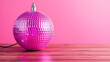 © Tark - Pink disco ball on wooden table and pink background. Generative AI
