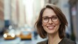 © liliyabatyrova - A cheerful woman wearing stylish glasses stands confidently in a vibrant urban setting. Her warm smile radiates joy against the backdrop of city life, filled with moving cars and sunlight
