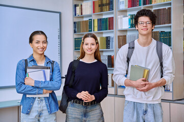 Wall Mural - Group of college students teenage girls and guy looking at camera inside library classroom