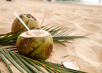 Wall Mural - Two fresh coconuts, ready to quench your thirst on a sandy beach.