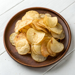 Crispy potato chips piled high on a rustic plate.