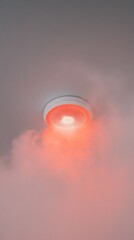 Poster - Smoke is triggering a smoke detector fixed on the ceiling, illuminating the surrounding area with a red light, indicating a potential fire hazard and emitting a loud alarm signal