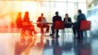 © Johannes - A blurred office meeting with business people sitting around a table, engaged in a discussion or training session. Blurred office and workplace background.