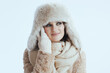 © Alliance - pensive woman in winter coat and fur hat touching face on white